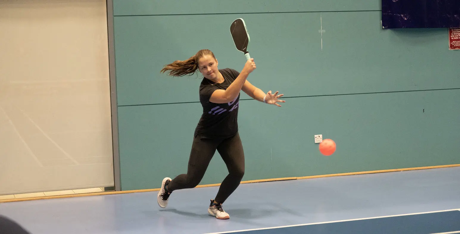 Female pickleball player hitting a forehand.